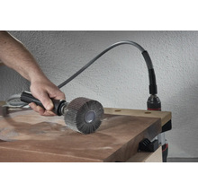 Person verwendet eine Schleifmopbürste auf einem Holzbrett, angetrieben von einer Bohrmaschine.