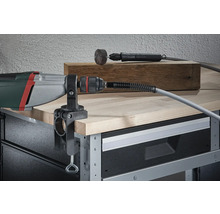Perceuse avec arbre flexible monté et serre-table sur un établi.