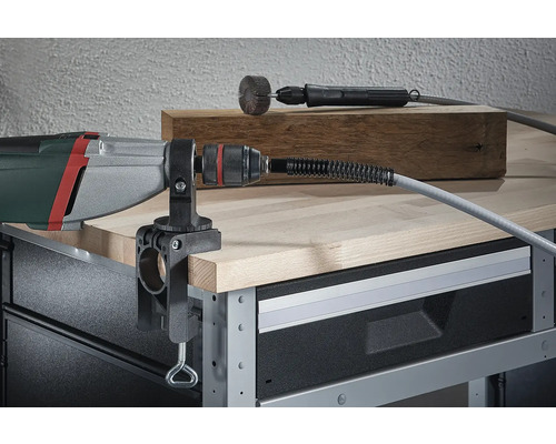 Perceuse avec arbre flexible monté et serre-table sur un établi.