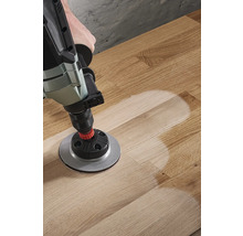 Bohrmaschine mit Schleifaufsatz auf Holzboden