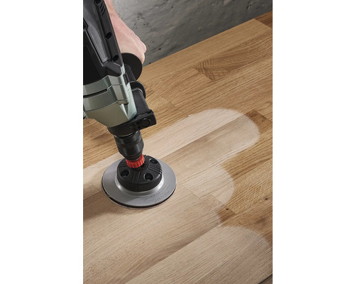 Perceuse avec accessoire de ponçage sur plancher en bois