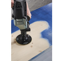 Eine Person benutzt eine Schleifmaschine, um Farbe von einem Holzbrett zu entfernen.
