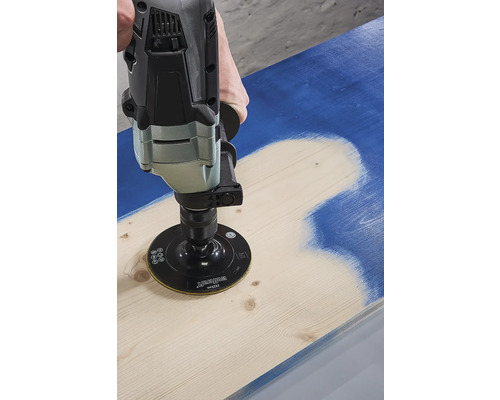 Une personne utilise une ponceuse pour enlever la peinture d''une planche de bois.