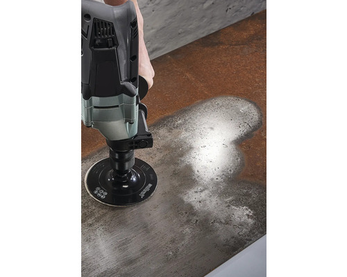 Une personne ponce une surface métallique avec une ponceuse.