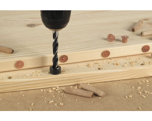 Perceuse avec foret à chevilles perçant un trou dans une planche de bois avec des marques