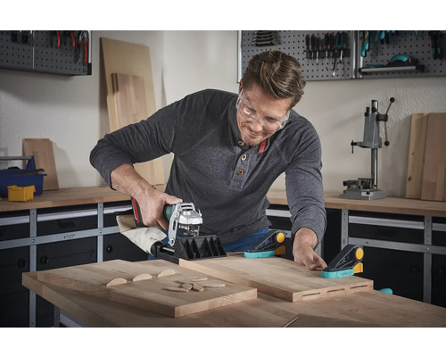 Mann benutzt eine Dübelfräse mit Holzverbindern und Werkstücken in einer Werkstatt.