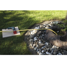 Une perceuse avec raccord d''eau et tuyau dans le jardin.