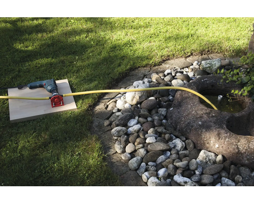 Une perceuse avec raccord d''eau et tuyau dans le jardin.