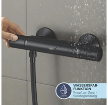 Robinet de douche noir avec fonction d''économie d''eau et main appuyant sur le bouton.