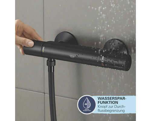 Robinet de douche noir avec fonction d''économie d''eau et main appuyant sur le bouton.