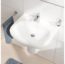 Weisses Waschbecken mit Armatur, Handtuchhalter und Becherhalter an einer gefliesten Wand