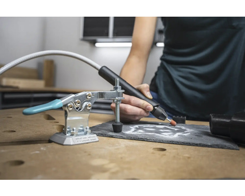 Scène d''établi avec graveur, serre-joint et plaque d''ardoise travaillée