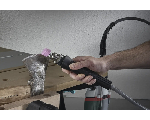 Une personne aiguise une hache avec un outil d''affûtage.