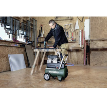 Un homme utilise un compresseur Metabo dans un atelier tout en travaillant sur une pièce.