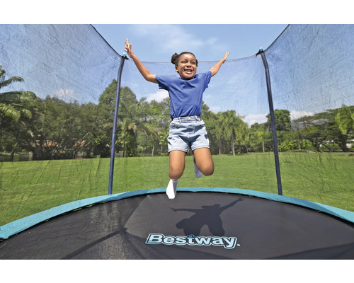Un enfant saute sur un trampoline de jardin avec filet de sécurité. Logo Bestway.