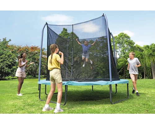Trampoline de jardin rectangulaire avec filet de sécurité et enfants jouant dans le jardin