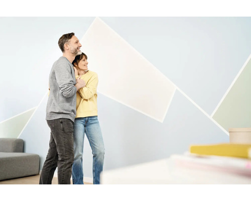 Couple regardant un design mural géométrique dans le salon.