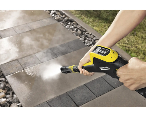 Une personne nettoie des pavés avec un nettoyeur haute pression Kärcher.