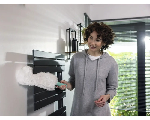 Femme nettoie radiateur avec plumeau