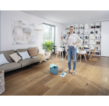 Frau mit Mopp und Eimer in einem hellen Wohnzimmer auf Holzboden