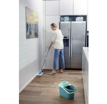 Frau wischt Fußboden mit einem Mopp in einer Küche.