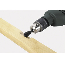 Une perceuse avec un embout de râpe travaille une pièce de bois.