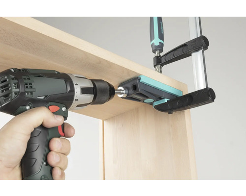 Visseuse sans fil perçant une planche de bois à travers un guide de perçage