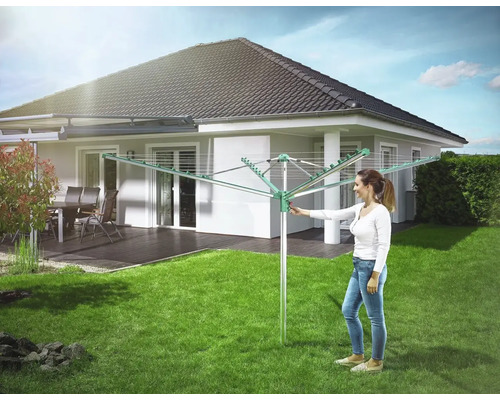 Drehflügelwäschespinne im Garten mit Frau, die sie bedient