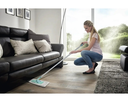 Frau wischt Holzboden mit einem Bodenwischer in einem Wohnzimmer