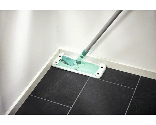 Serpillière sur carrelage foncé contre un mur blanc