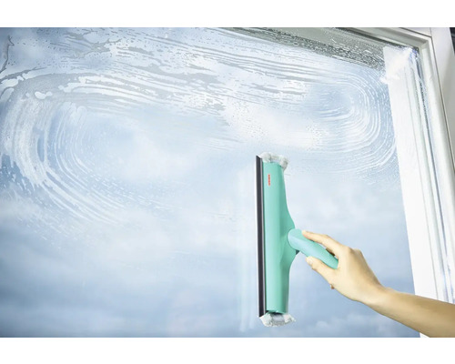 Une main nettoie une surface vitrée avec un lave-vitre