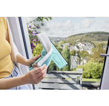 Frau benutzt einen Fensterwischer mit Mikrofaserbezug zur Reinigung eines Fensters