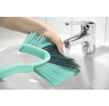 Main sous le robinet rinçant une brosse dans le lavabo