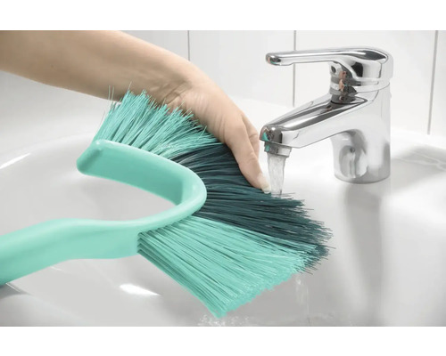 Main sous le robinet rinçant une brosse dans le lavabo