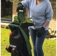 Une femme utilise un broyeur de jardin sans fil Bosch dans le jardin.