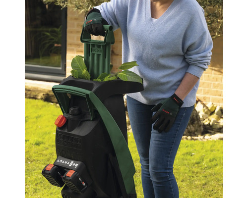 Une femme utilise un broyeur de jardin sans fil Bosch dans le jardin.