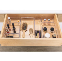 Tiroir ouvert avec des inserts d'organisation transparents pour les cosmétiques et les brosses.