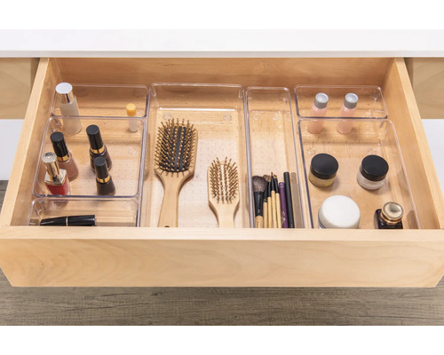 Tiroir ouvert avec des inserts d'organisation transparents pour les cosmétiques et les brosses.