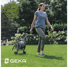 Frau zieht einen Schlauchwagen durch den Garten