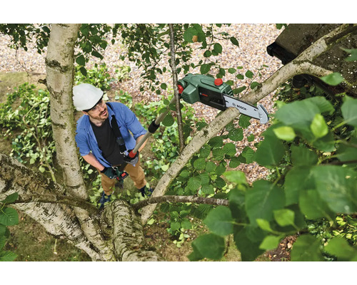 Homme portant un casque et un équipement de sécurité, utilisant une tronçonneuse d'élagage Bosch dans un arbre.