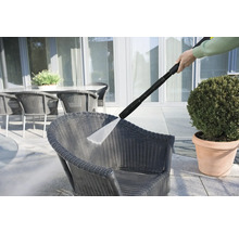 Nettoyeur haute pression en cours d'utilisation pour nettoyer une chaise en osier à l'extérieur.