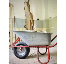 Brouette sur un chantier devant un mur endommagé