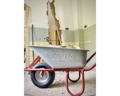 Brouette sur un chantier devant un mur endommagé