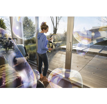 Femme nettoie les fenêtres avec un aspirateur de fenêtre pour une propreté sans traces.