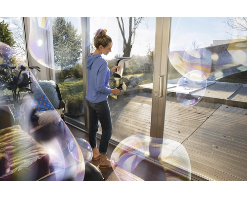 Femme nettoie les fenêtres avec un aspirateur de fenêtre pour une propreté sans traces.