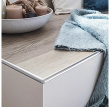 Detailansicht einer Kommode mit Holzoberfläche und hellblauem Überwurf