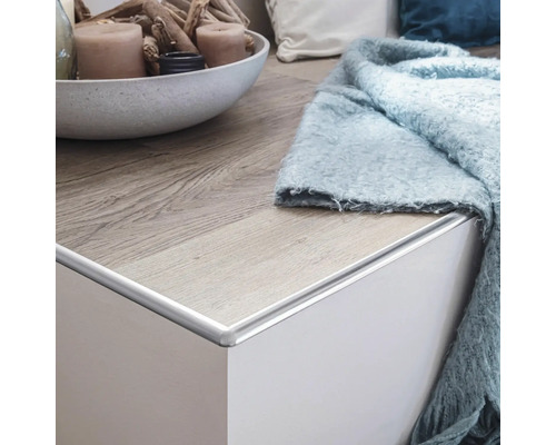 Detailansicht einer Kommode mit Holzoberfläche und hellblauem Überwurf