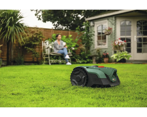 Scène avec robot tondeuse à gazon sur une pelouse et une femme assise sur un banc