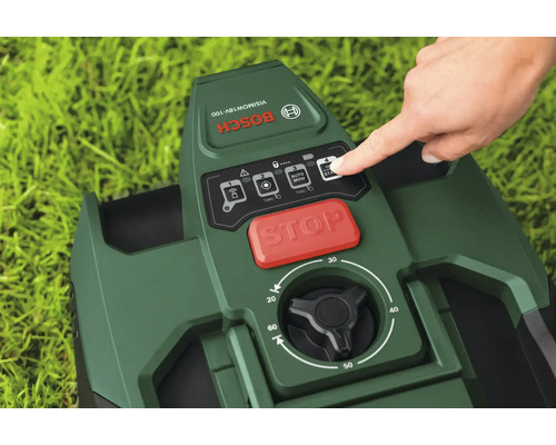 Panneau de commande d'un robot tondeuse Bosch avec une main appuyant sur le bouton de démarrage