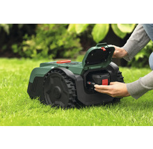 Tondeuse autoportée avec batterie insérée dans l'herbe